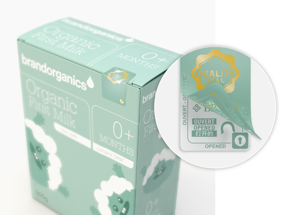 A green carton of “Brandorganics Organic First Milk” for 0+ months, featuring a tamper-evident quality seal on the top flap. A magnified view highlights the seal, which displays an “OPENED” void effect to indicate tampering. The seal includes a “Quality Seal” logo and a clear tamper-indicating design, ensuring product integrity and consumer trust.